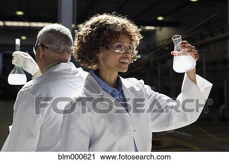 Stock Image - African scientists examining beakers of liquid in factory. Fotosearch