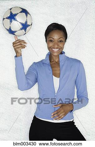 Stock Image - African woman balancing soccer ball. Fotosearch
