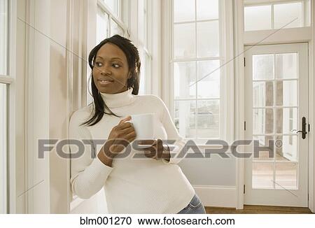 Stock Image - African woman holding coffee cup. Fotosearch