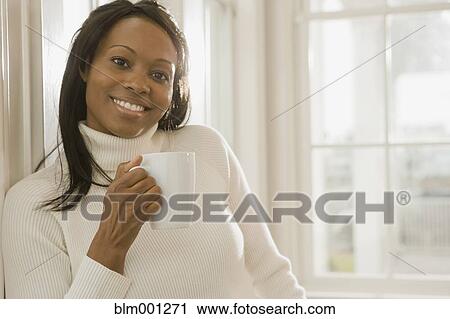 Stock Image - African woman holding coffee cup. Fotosearch