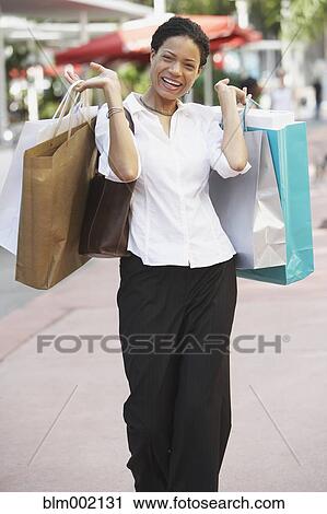 Stock Image - African woman holding shopping bags. Fotosearch