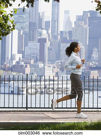 Stock Photograph - African woman jogging in urban park. Fotosearch