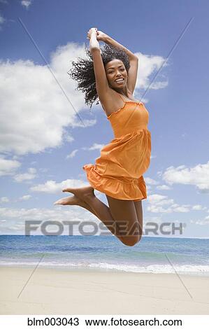 African woman jumping in mid-air at beach View Large Photo Image Stock Image - African woman jumping in mid-air at beach. Fotosearch