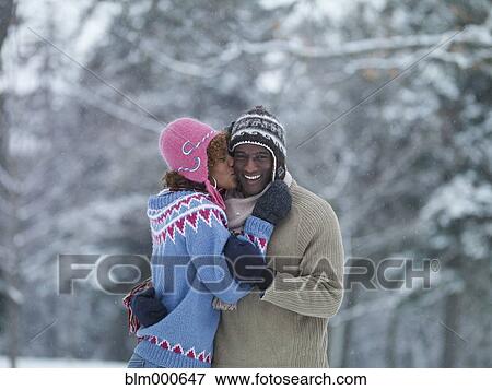 Stock Photo - African woman kissing boyfriend in the snow. Fotosearch