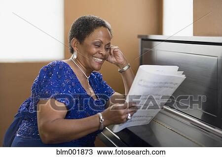 Stock Image - African woman leaning on closed piano. Fotosearch