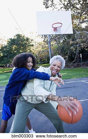 Stock Image - African woman playing basketball with granddaughter. Fotosearch