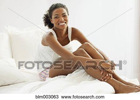 Stock Image - African woman sitting in bed. Fotosearch