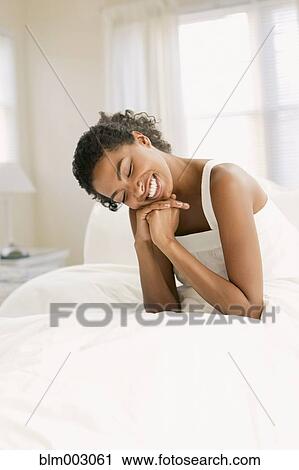 Stock Image - African woman smiling in bed. Fotosearch