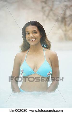 Stock Image - African woman standing in hot tub. Fotosearch