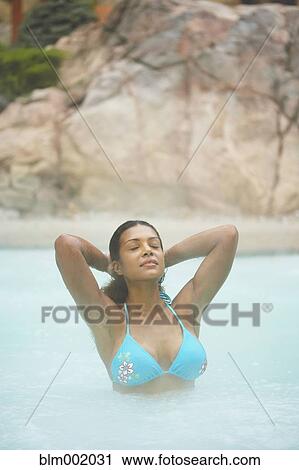 Stock Image - African woman standing in hot tub. Fotosearch