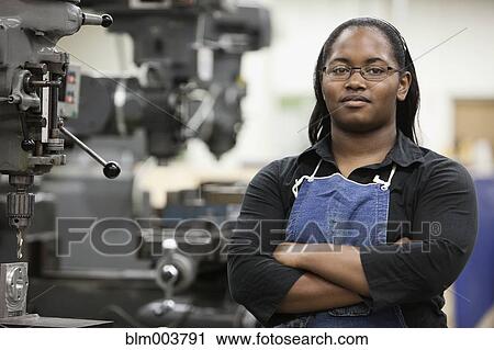 Stock Image - African woman standing in machine tooling plant. Fotosearch