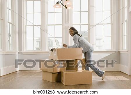 Stock Photo - African woman using laptop on boxes. Fotosearch