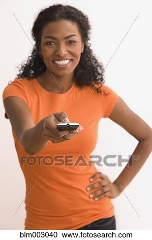 Stock Image - African woman using remote control. Fotosearch