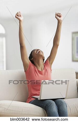 African woman with arms raised using laptop View Large Photo Image Stock Image - African woman with arms raised using laptop. Fotosearch