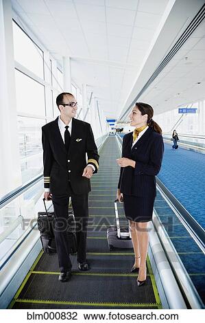 Stock Image - Airline employees on moving walkway in airport. Fotosearch