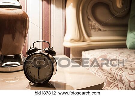 Stock Image - Alarm clock on bedside table. Fotosearch