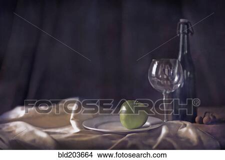Picture - Apple, wine glass and bottle on tablecloth. Fotosearch