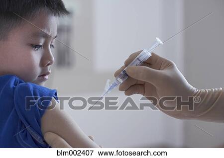 Stock Photo - Asian boy getting shot at hospital. Fotosearch