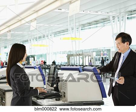 Stock Image - Asian businessman checking in at airport. Fotosearch