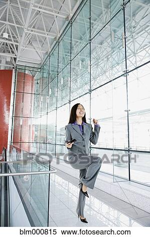 Stock Photography - Asian businesswoman celebrating in airport. Fotosearch