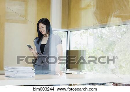 Picture - Asian businesswoman looking at cell phone. Fotosearch