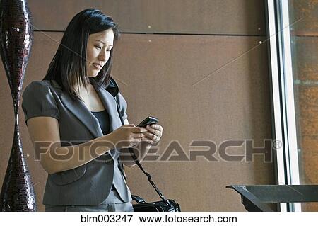Stock Photo - Asian businesswoman looking at cell phone. Fotosearch