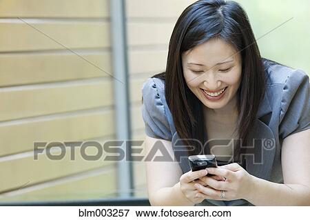 Stock Photo - Asian businesswoman looking at cell phone. Fotosearch
