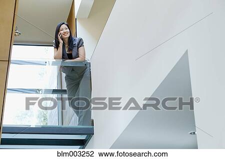 Stock Image - Asian businesswoman talking on cell phone in office. Fotosearch