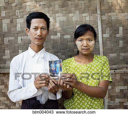 Stock Image - Asian couple holding photograph. Fotosearch