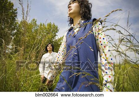Picture - Asian couple standing in tall grass. Fotosearch