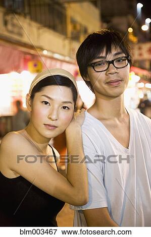 Stock Photo - Asian couple standing on urban street. Fotosearch