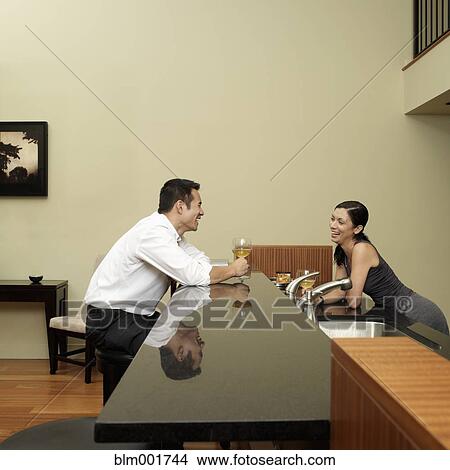 Picture - Asian couple talking in kitchen. Fotosearch