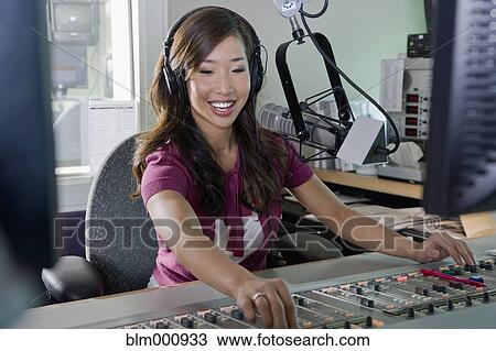 Stock Image - Asian dj working at radio station. Fotosearch
