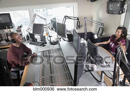 Stock Photograph - Asian dj working at radio station with co-worker. Fotosearch