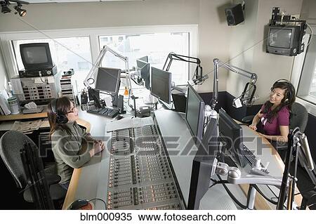 Stock Photography - Asian dj working at radio station with co-worker. Fotosearch