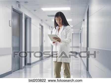 Stock Image - Asian doctor reading medical chart in hospital. Fotosearch