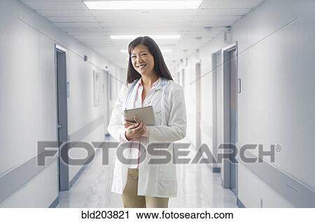 Stock Image - Asian doctor smiling in hospital. Fotosearch
