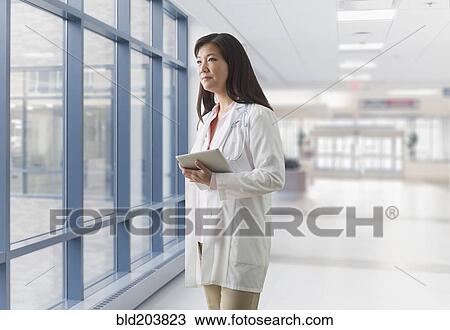 Stock Image - Asian doctor walking in hospital. Fotosearch