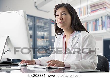 Stock Photography - Asian doctor working at computer in hospital. Fotosearch