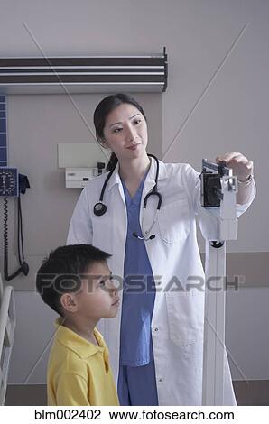 Asian female doctor weighing boy View Large Photo Image Stock Image - Asian female doctor weighing boy. Fotosearch