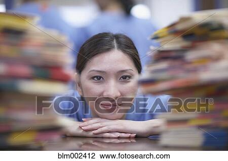 Asian female medical professional between stacks of charts View Large Photo Image Stock Image - Asian female medical professional between stacks of charts. Fotosearch