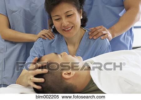 Stock Photography - Asian female medical professional smiling at patient. Fotosearch