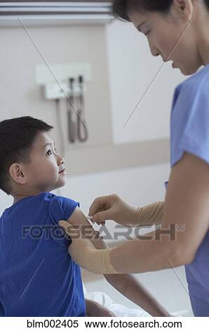 Stock Photography - Asian female medical professional preparing boy for shot. Fotosearch