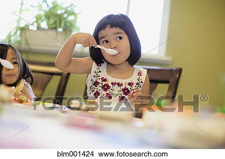 Picture - Asian girls eating cake. Fotosearch