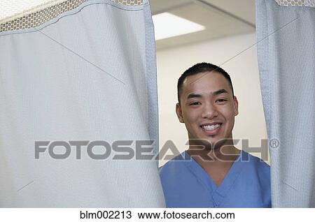 Stock Image - Asian male medical professional opening curtain. Fotosearch