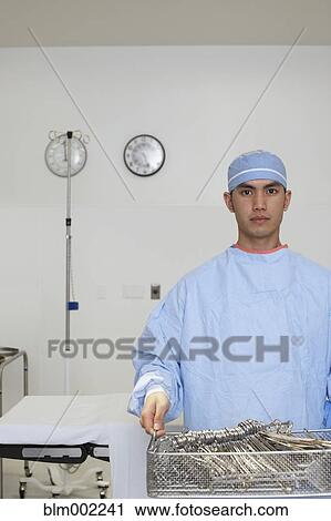 Stock Image - Asian male medical professional carrying surgical tools. Fotosearch