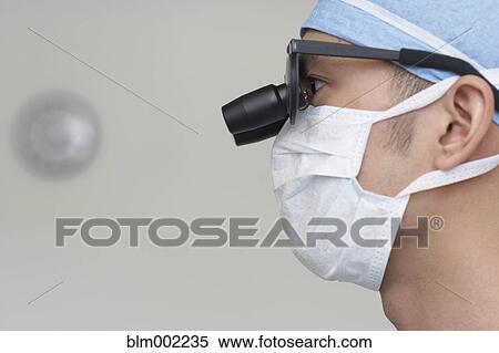 Stock Photography - Asian male medical professional wearing magnifying glasses. Fotosearch