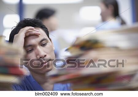 Stock Photo - Asian male medical professional with hand on head. Fotosearch