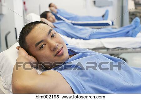Stock Photography - Asian male medical professional with hands behind head. Fotosearch