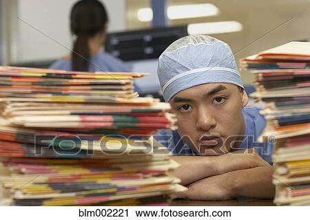 Stock Image - Asian male medical professional yawning. Fotosearch